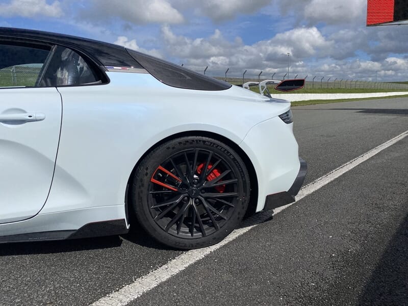Détail roue arrière Alpine A110R noire avec étriers rouges, sur circuit.