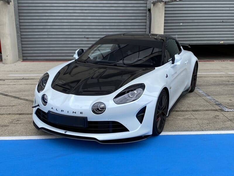 Alpine A110R blanche et noire garée dans la voie des stands.