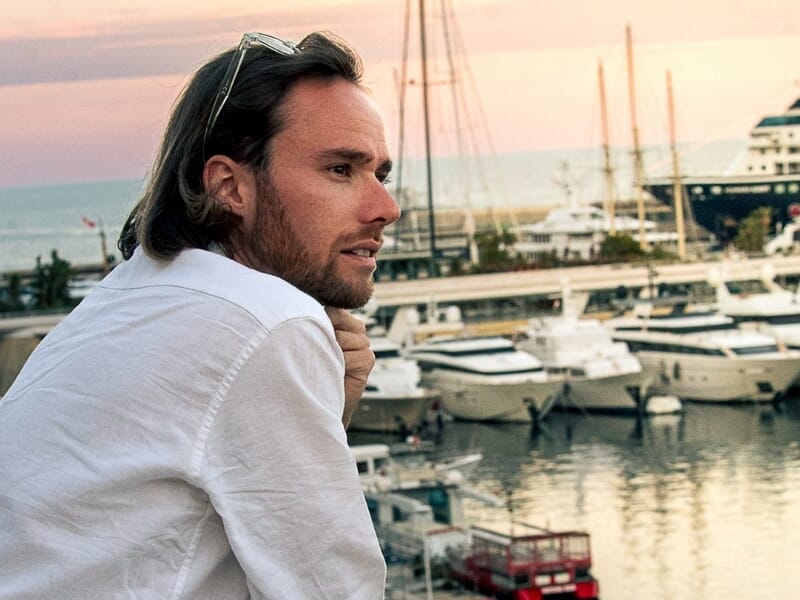 Homme aux cheveux longs et chemise blanche lors d'une séance photo portrait en bord de mer à Nice