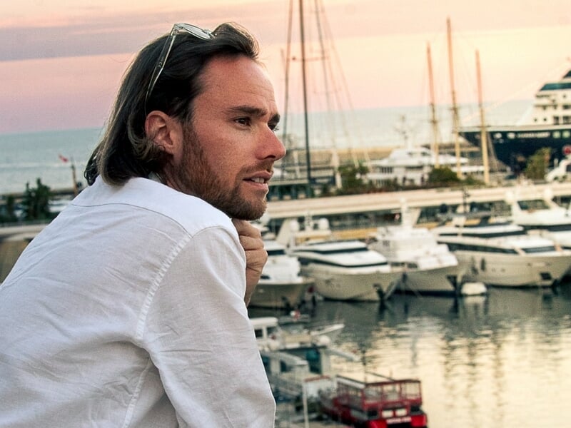 Homme aux cheveux longs et chemise blanche lors d'une séance photo portrait en bord de mer à Nice