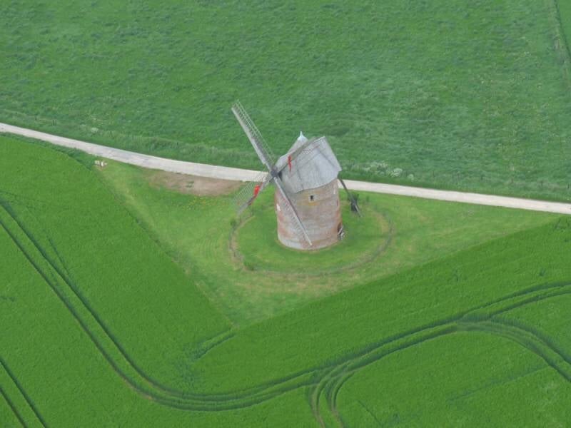 Vue aérienne sur un moulin construit au milieu des champs verdoyants.