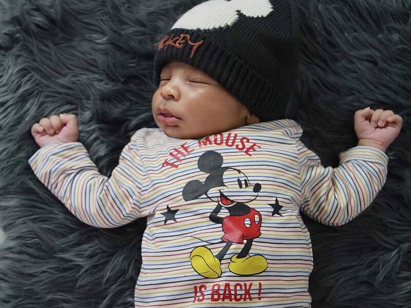 Nouveau-né dormant sur un tapis gris en fourrure, image prise par une photographe bébé à Dijon.