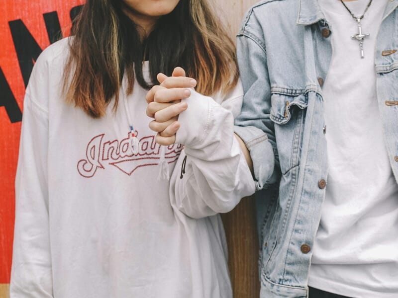 Shooting photo couple Dijon, deux amoureux en sweat et veste en jean se tenant tendrement la main.