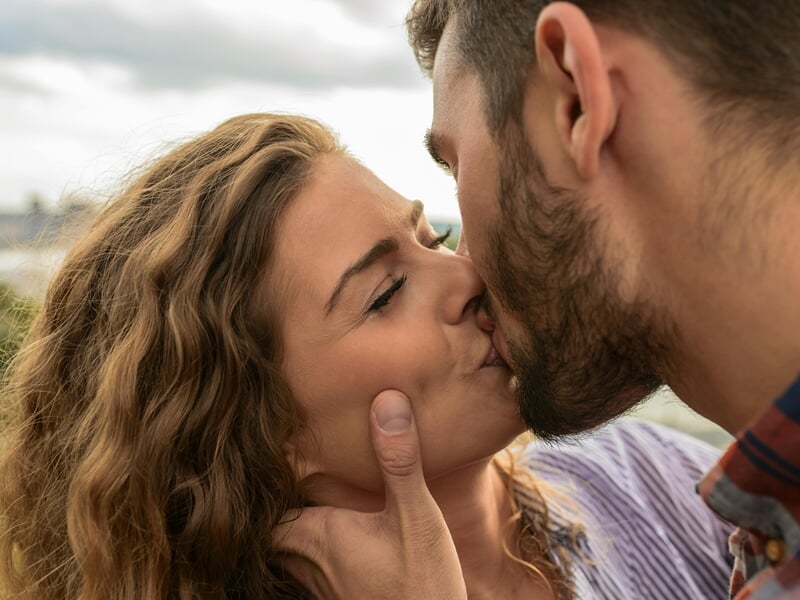 Shooting photo couple Dijon, gros plan romantique d’un couple échangeant un baiser tendre en extérieur.