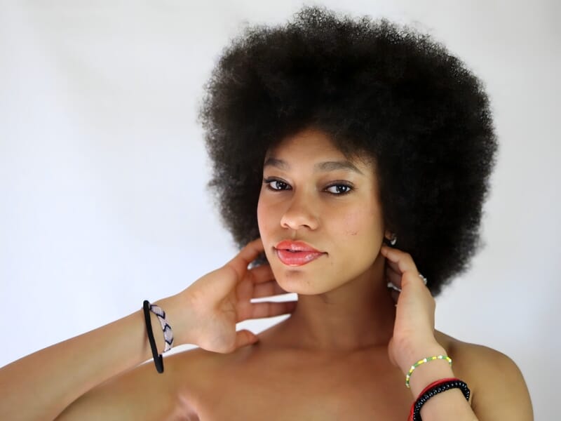 Séance photo portrait Dijon, jeune femme au style naturel posant avec confiance, cheveux afro volumineux et regard intense.