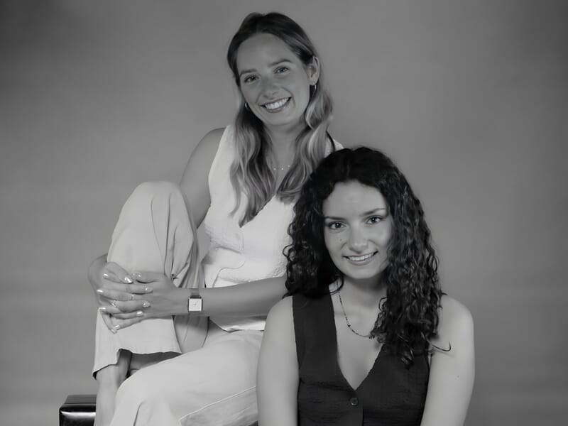 Séance photo portrait Dijon, photo en noir et blanc de deux jeunes femmes assises en studio avec un sourire complice.