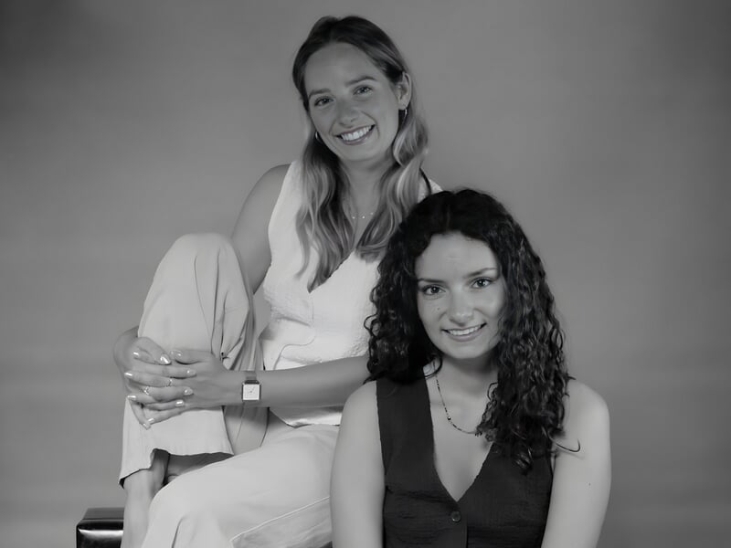 Séance photo portrait Dijon, photo en noir et blanc de deux jeunes femmes assises en studio avec un sourire complice.