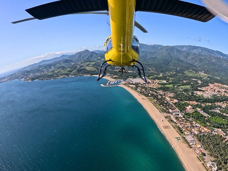 Vue aérienne depuis un hélicoptère jaune au-dessus d’Argelès-sur-Mer et de la côte
