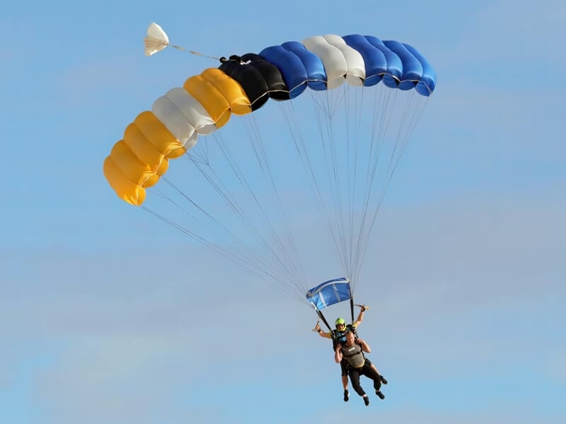 Parachutistes en tandem sous une grande voile multicolore en plein vol