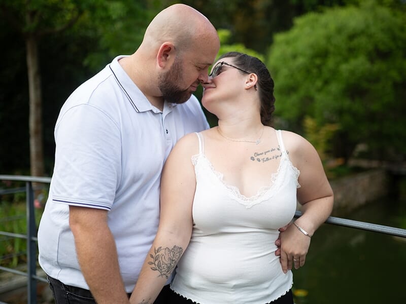 Un couple s'embrasse tendrement près d'un plan d'eau lors d'un shooting avec une photographe couple à Angers.