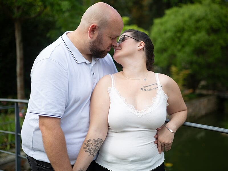 Un couple s'embrasse tendrement près d'un plan d'eau lors d'un shooting avec une photographe couple à Angers.