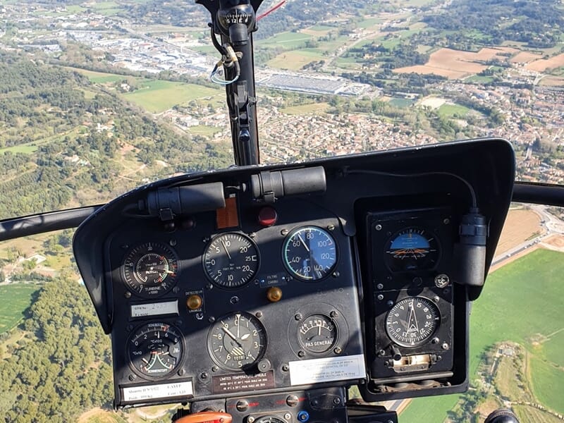 Vue du tableau de bord d'un hélicoptère en vol au-dessus d'un paysage rural lors d'un vol en hélicoptère près de Brignoles.