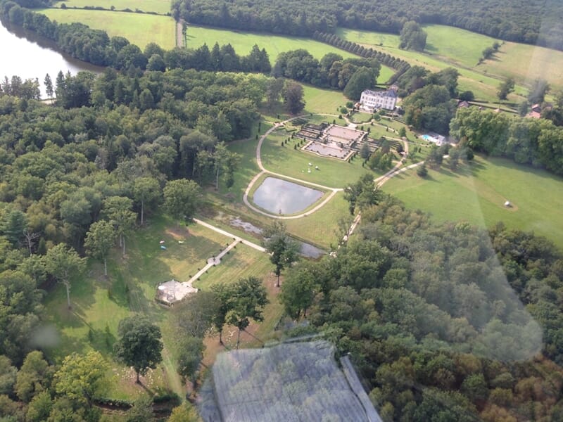 Vue aérienne d'un domaine avec des arbres, un étang et des bâtiments lors d'un vol en hélicoptère près de Brignoles.