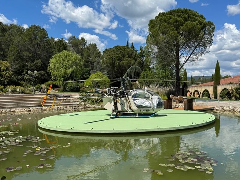 Petit hélicoptère posé sur une plateforme flottante au milieu d'un bassin avec des nénuphars lors d'un vol en hélicoptère près de Brignoles.