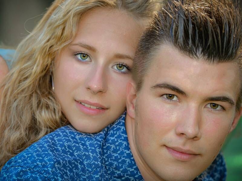 Portrait rapproché d'un jeune couple souriant, la femme aux cheveux blonds et l'homme aux cheveux courts foncés.