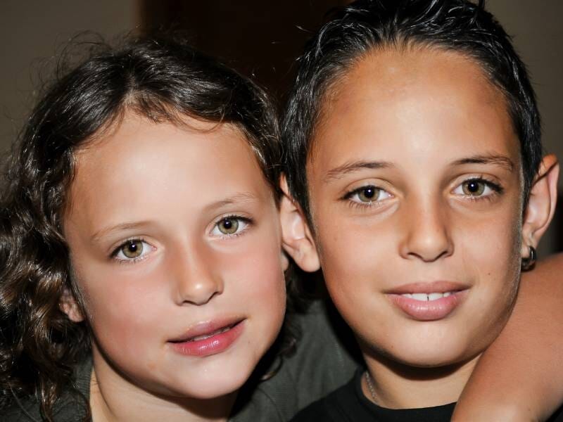 Deux enfants souriants, un garçon et une fille, posant ensemble avec complicité et lumière douce, à Argelès.