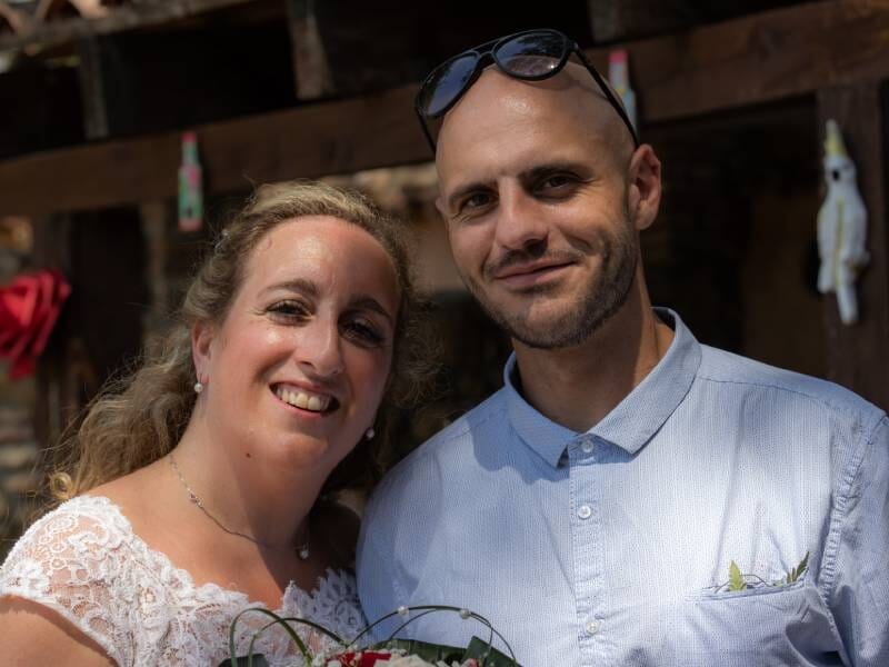 Un jeune couple nouvellement marié s'enlace et sourit.