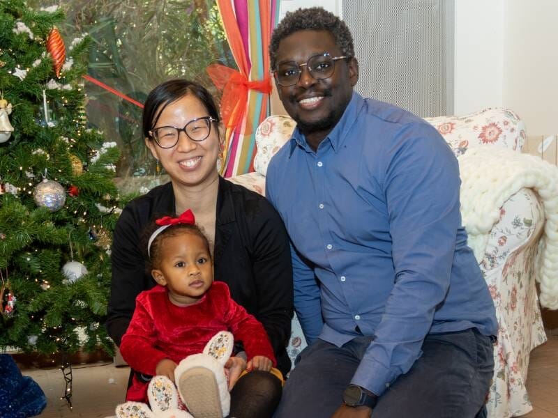 Un couple prend la pose avec son enfant sur les genoux.