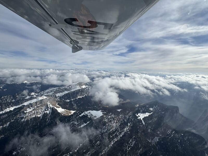 Pilotage avion ULM Lac du Bourget avec paysages alpins et nuages flottant au-dessus des sommets.