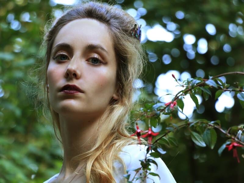 Une femme blonde et bien maquillée prend la pose et fixe l'objectif.