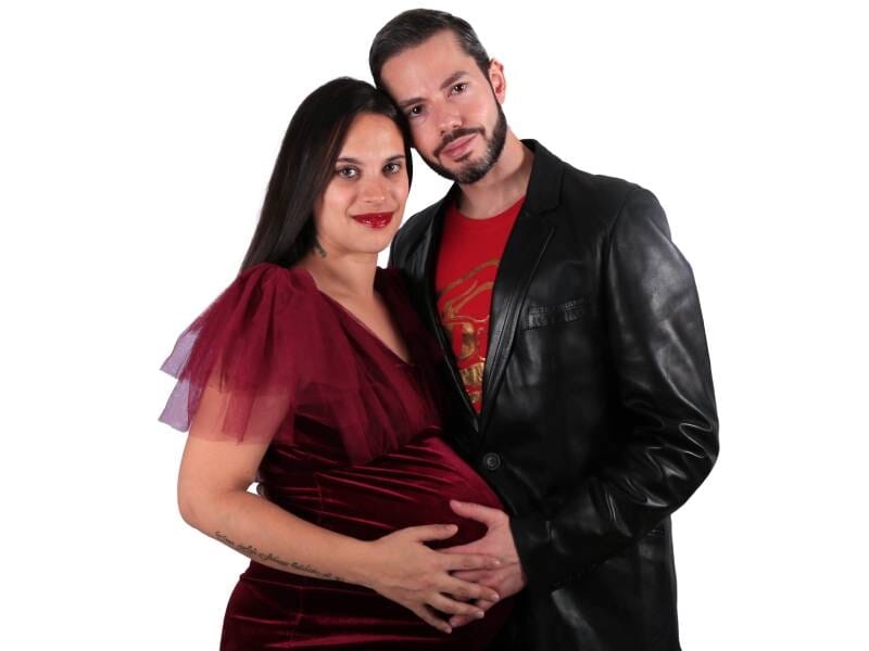 Un couple prend la pose, les mains sur le ventre rond de la femme.