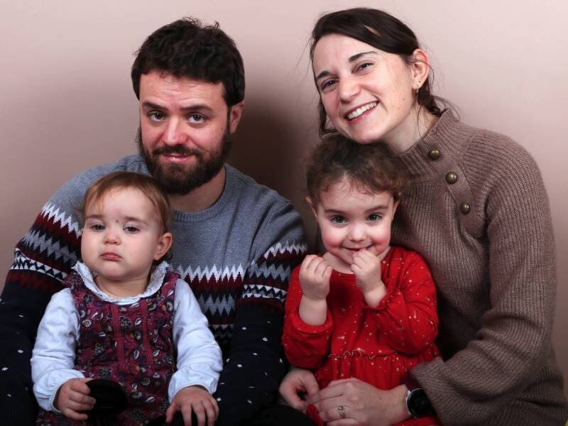 Deux parents prennent la pose avec leurs deux enfants sur les genoux.