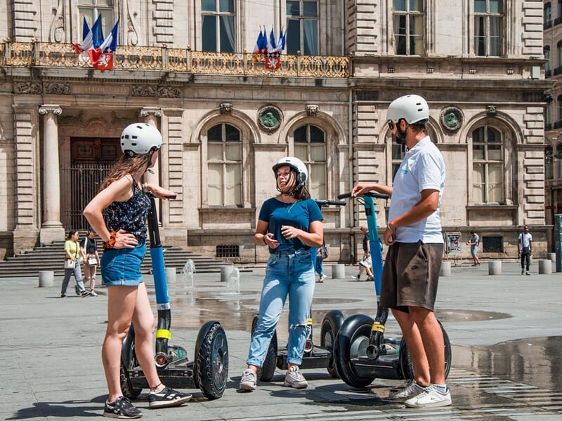 Découverte en segway Lyon devant l’Hôtel de Ville, le guide échange avec deux participantes sur l’histoire locale.