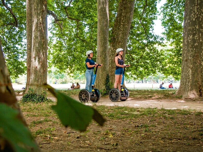 Promenade en segway Lyon dans le parc de la Tête d’Or, deux femmes en gyropode évoluent sous les grands arbres.