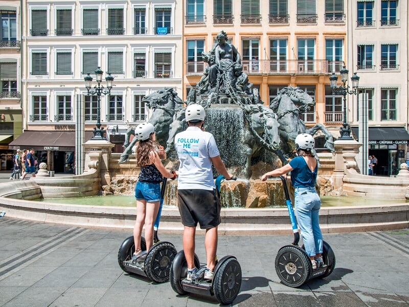 Balade en segway Lyon devant la fontaine Bartholdi, trois participants découvrent la place des Terreaux en gyropode.