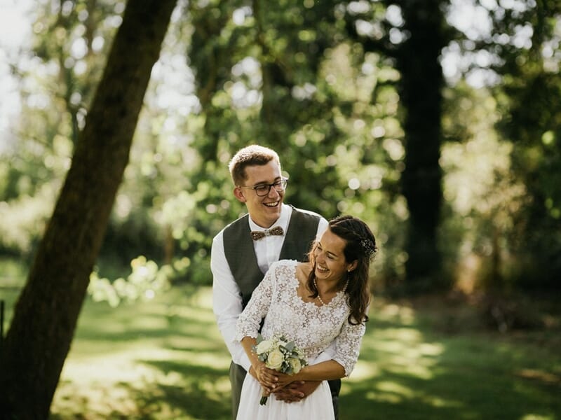 Jeune couple de mariés souriants dans un parc ensoleillé, lors d'un shooting avec un photographe de couple à Amiens.