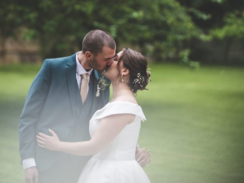 Couple de mariés s'embrassant dans un jardin, lors d'un shooting avec un photographe de couple à Amiens.