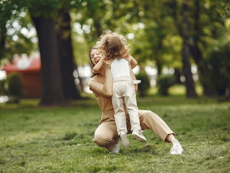 Une femme accroupie accueille joyeusement sa petite fille lors d'un shooting photo famille à Amiens.