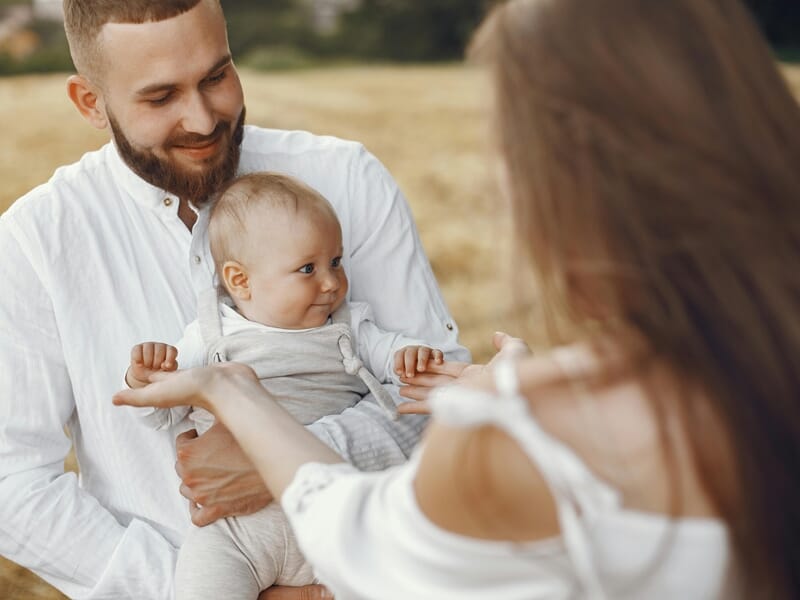 Un homme souriant tient un bébé dans ses bras lors d'un shooting photo famille à Amiens.