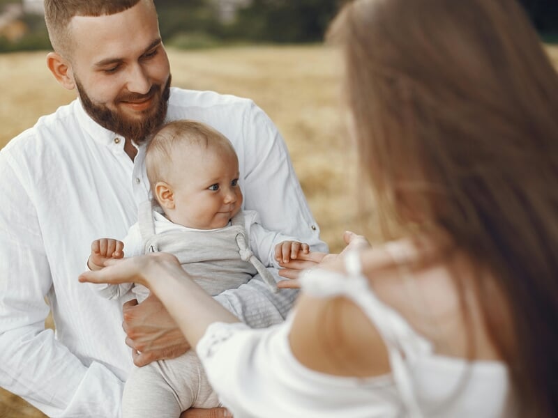 Un homme souriant tient un bébé dans ses bras lors d'un shooting photo famille à Amiens.