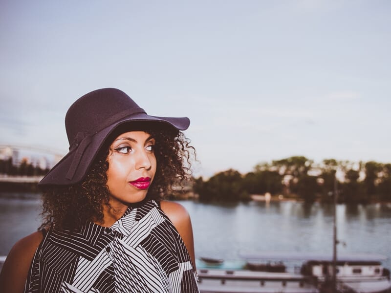 Femme aux cheveux bouclés portant un chapeau violet lors d'un shooting photo lifestyle à Amiens.