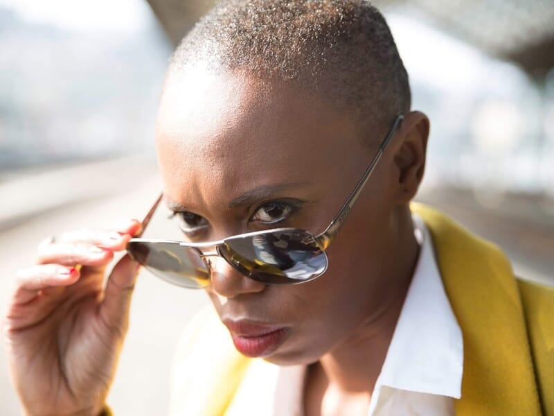 Femme au regard perçant baissant ses lunettes de soleil lors d'un shooting photo lifestyle à Amiens.
