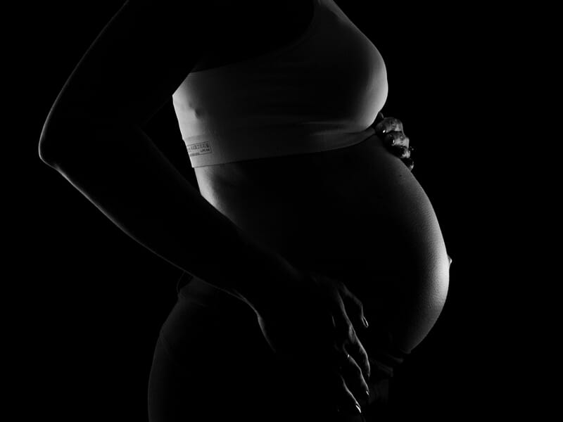 Silhouette en contre-jour d'une femme enceinte lors d'un shooting avec un photographe de grossesse près de Strasbourg.