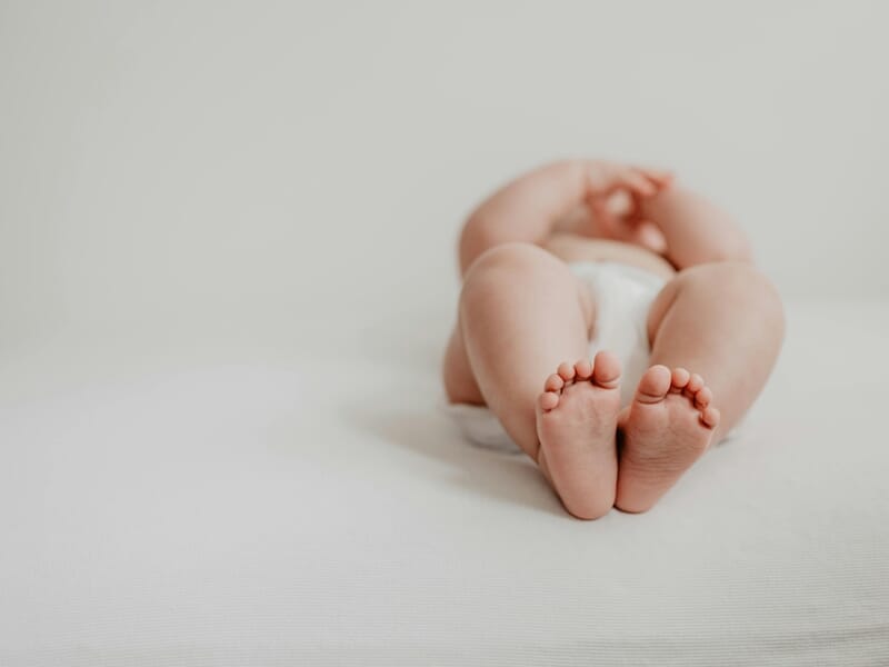 Gros plan sur les pieds d'un bébé allongé sur un lit blanc lors d'un shooting photo bébé près de Strasbourg.