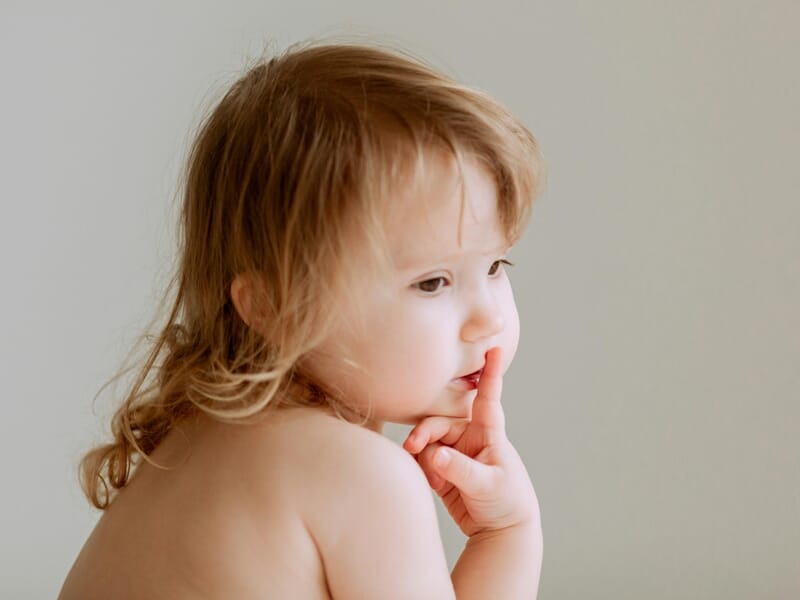 Enfant aux cheveux blonds regardant pensivement sur le côté lors d'un shooting photo bébé près de Strasbourg.