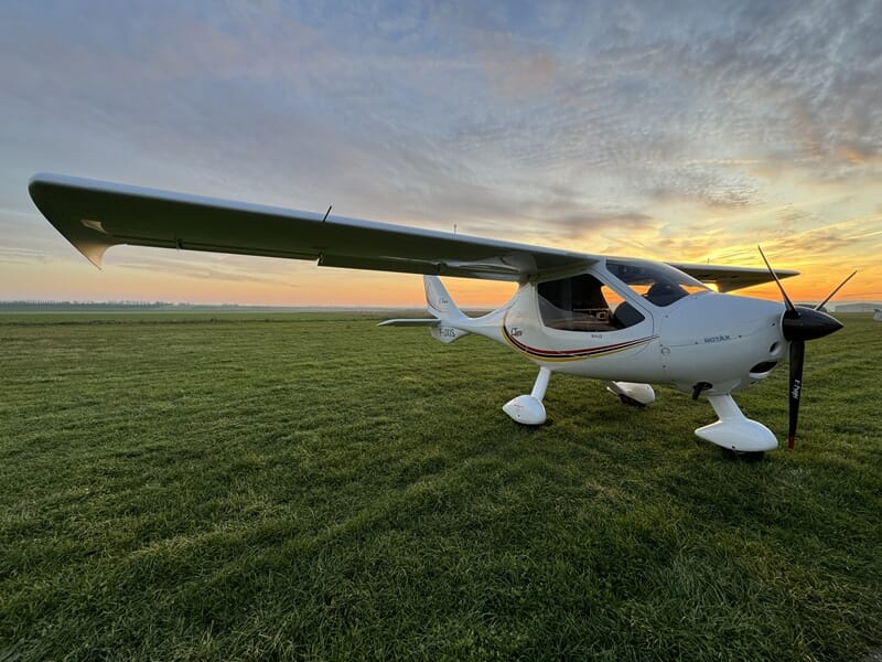 Avion ultraléger blanc stationné sur une piste d'herbe lors d'un vol en ULM près de Reims.