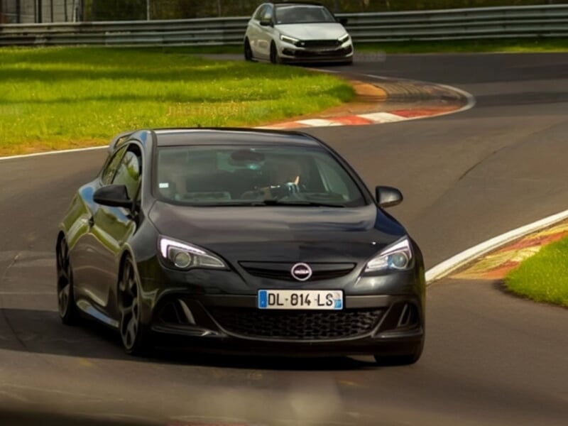 Opel sportive noire suivie d’une autre voiture blanche dans un virage du circuit de Nürburgring.