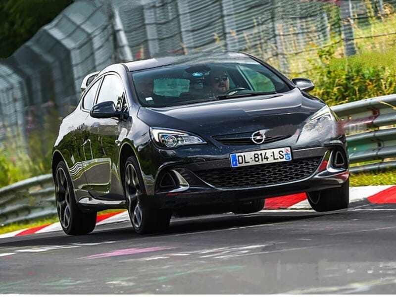 Opel noire en action sur le circuit de Nürburgring, roues braquées et performance automobile en piste.