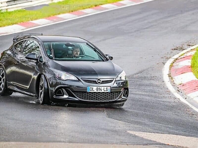 Voiture Opel noire en plein virage serré sur le circuit de Nürburgring, démonstration de conduite sportive.