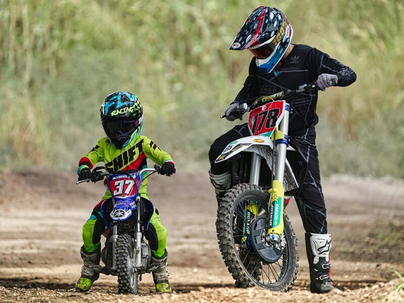 Deux enfants en tenue de moto tout-terrain posent avec leurs motos sur un chemin lors d'un stage moto-cross enfant près de Nancy.