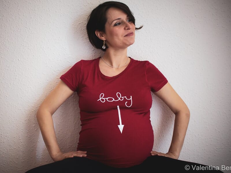 Femme enceinte en t-shirt rouge avec inscription baby lors d'un shooting avec une photographe grossesse à Béziers.