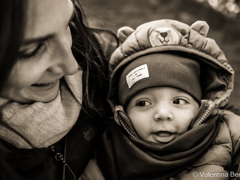 Une femme souriante regarde un bébé emmitouflé lors d'un shooting photo famille à Béziers.