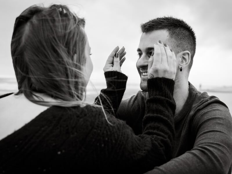 Une femme joue avec les mains de son compagnon lors d'un shooting avec une photographe de couple à Béziers.