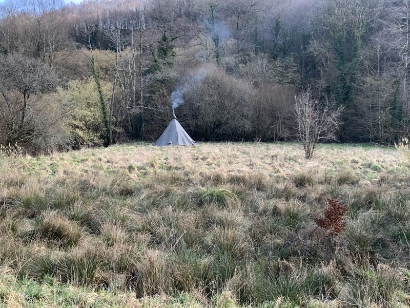 Tipi avec de la fumée s'échappant du sommet lors d'un stage de survie à Le Saint.