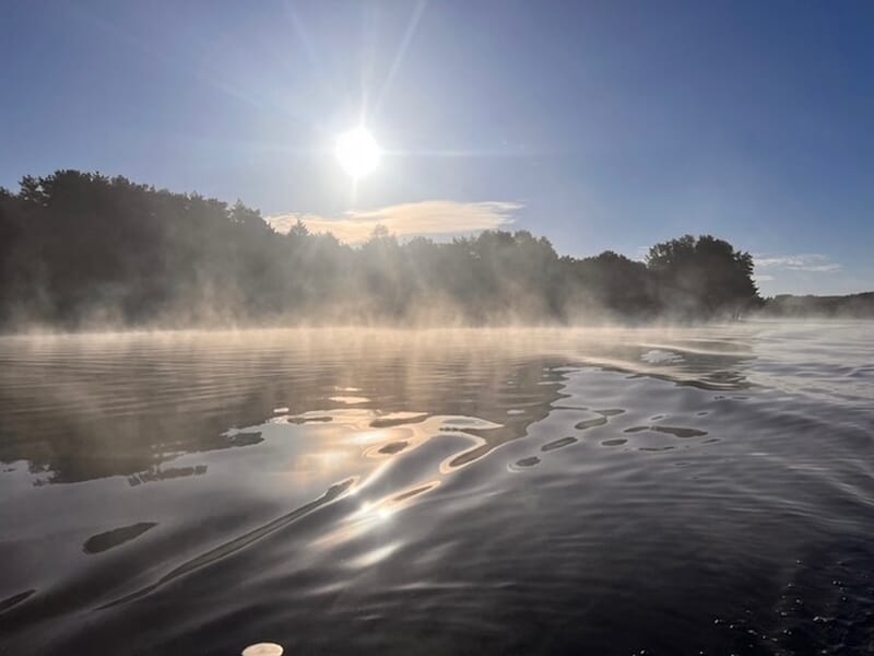 Lever de soleil sur un lac avec une légère brume flottant au-dessus de l'eau calme lors d'un stage de pêche près de Limoges. 