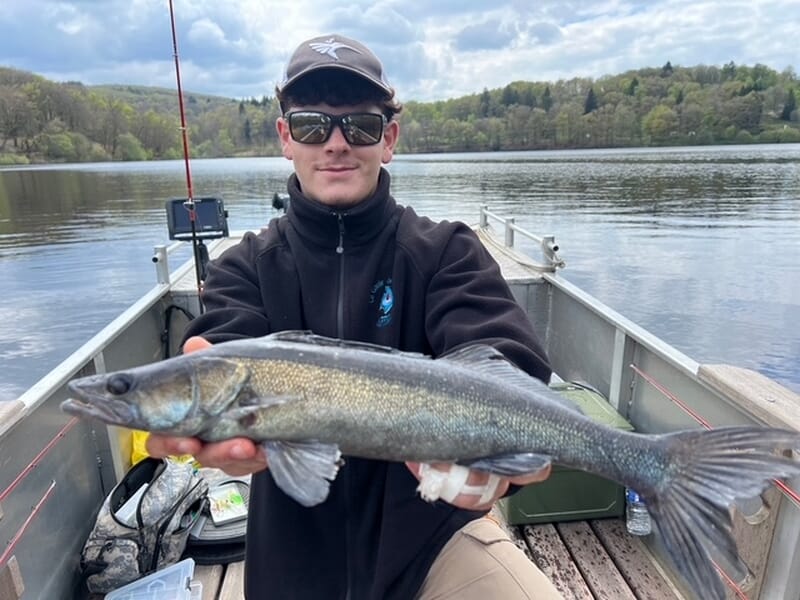 Homme en bateau tenant un poisson allongé lors d'un stage de pêche près de Limoges. 